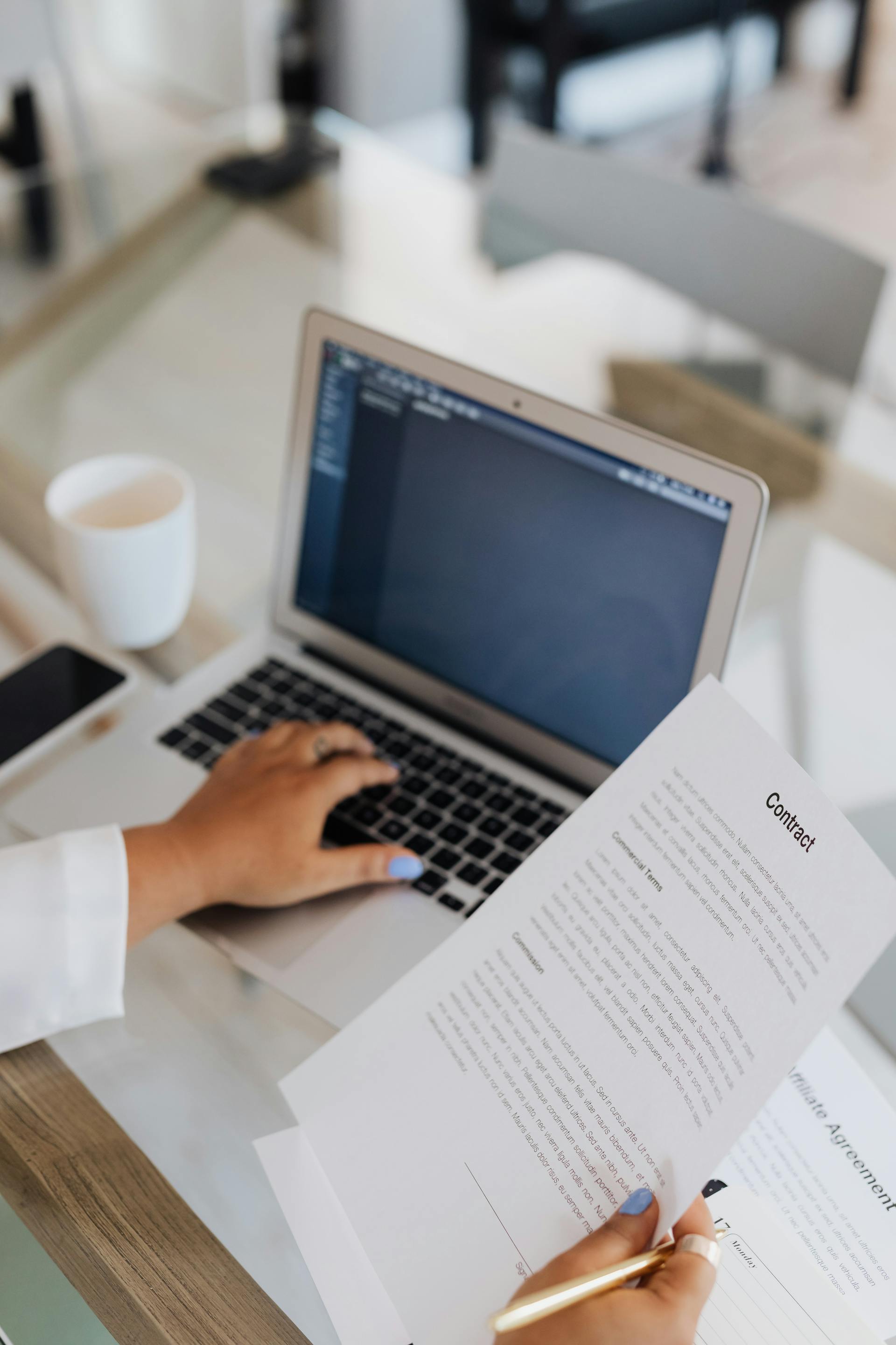 Person holding legal document while using laptop
