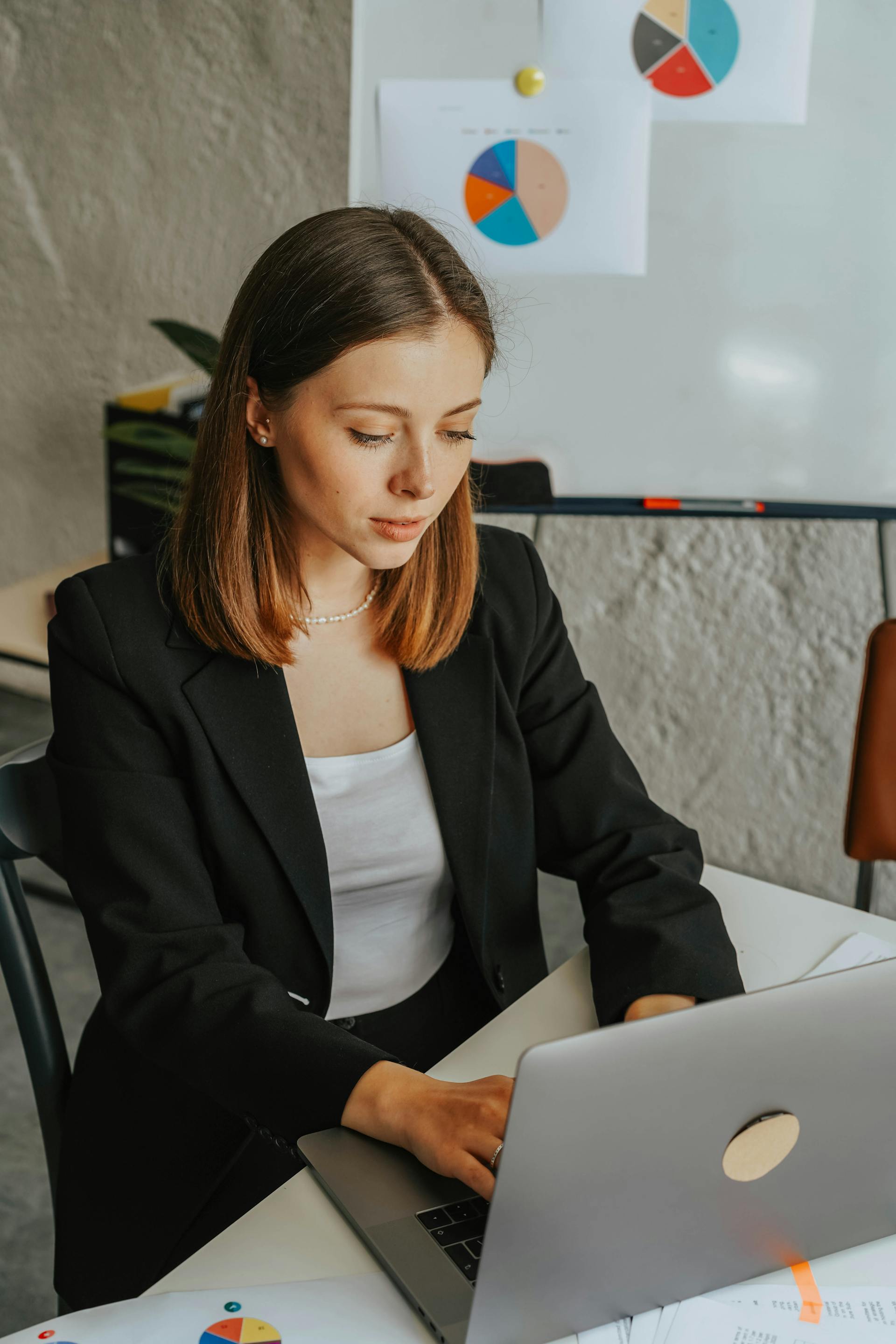 Professional woman in blazer using laptop with charts